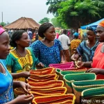 기니 여행자 대상 사기 유형 - A busy open-air market scene in Guinea during daytime, showcasing vibrant traditional crafts and sou...